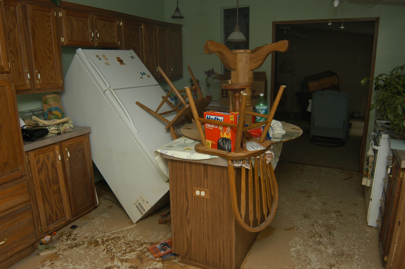 Kitchen in Hazel Crest after a flood, refrigerator tipped and cabinets soaked, before extraction